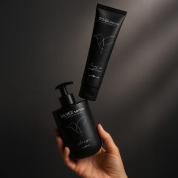 Eine Hand hält eine schwarze Shampoo-Flasche von Silver Sense, darüber schwebt eine Tube Leave-in-Conditioner.